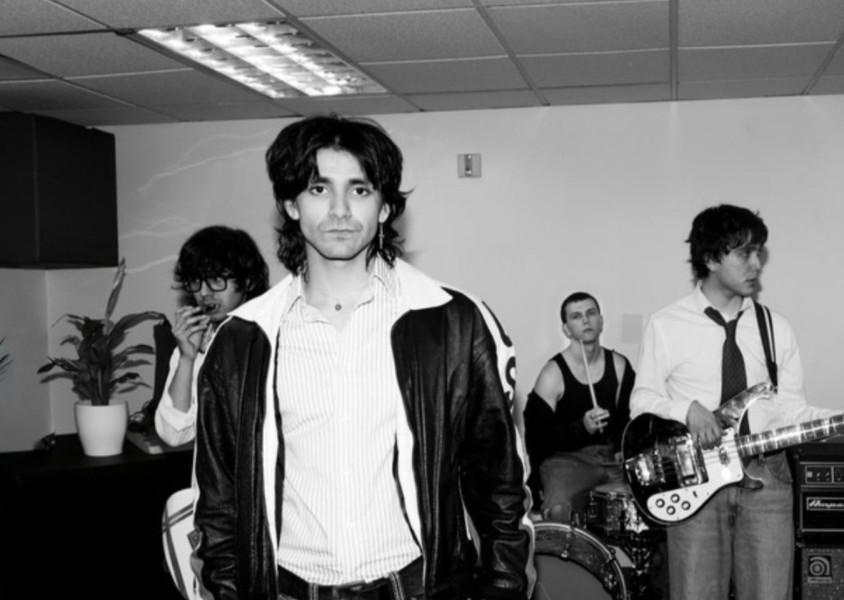 four men stand in a band practice roomx
